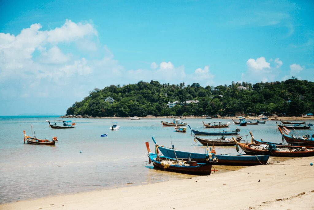 Traditional longtail boats anchored on a quiet tropical beach in Koh Samui, Thailand, a popular stop for backpacking Koh Samui travelers.