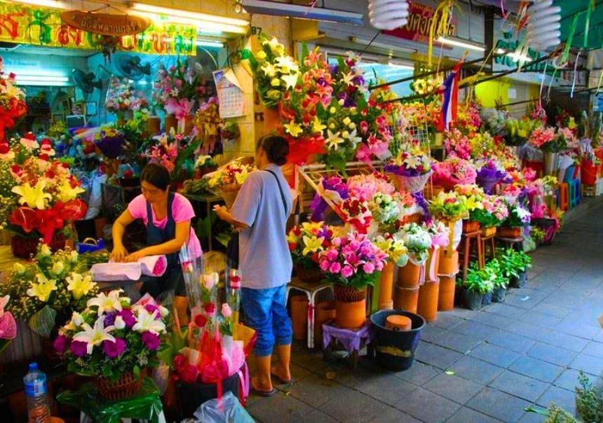 Flower sellers surrounded by colourful bouquets and garlands at Pak Khlong Talat in Bangkok