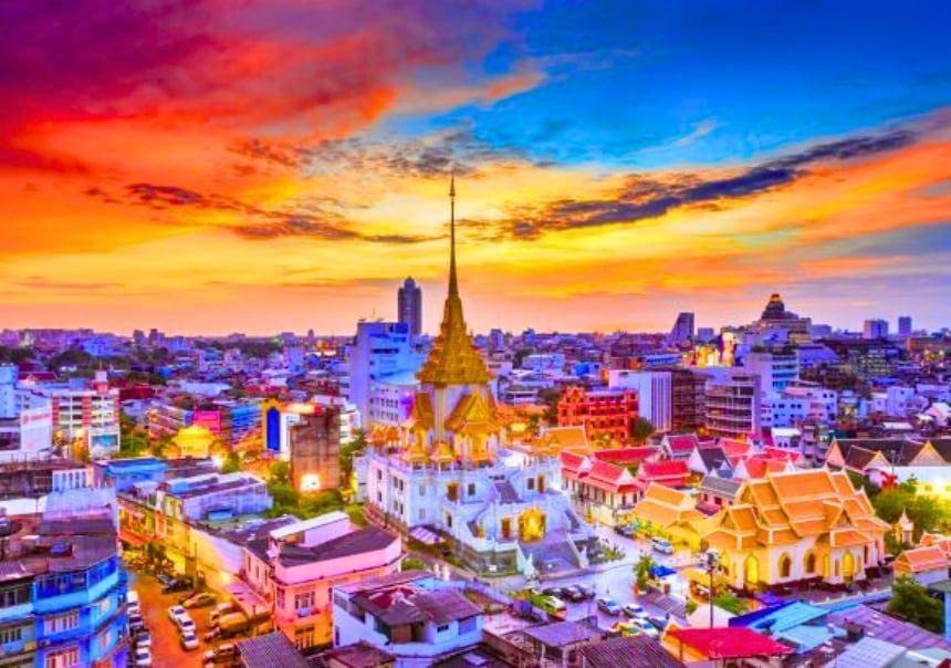 Wat Traimit temple complex rising above the rooftops of Bangkok Chinatown at sunset